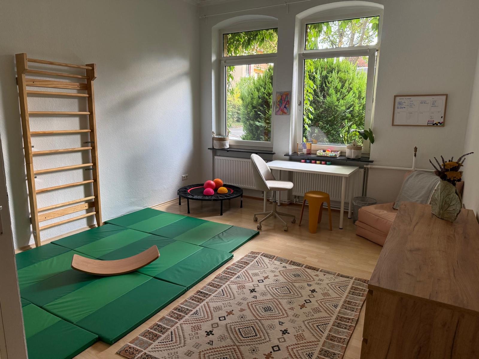 Bewegungsraum der Praxis mit Sprossenwand, Matten und Balanceboard