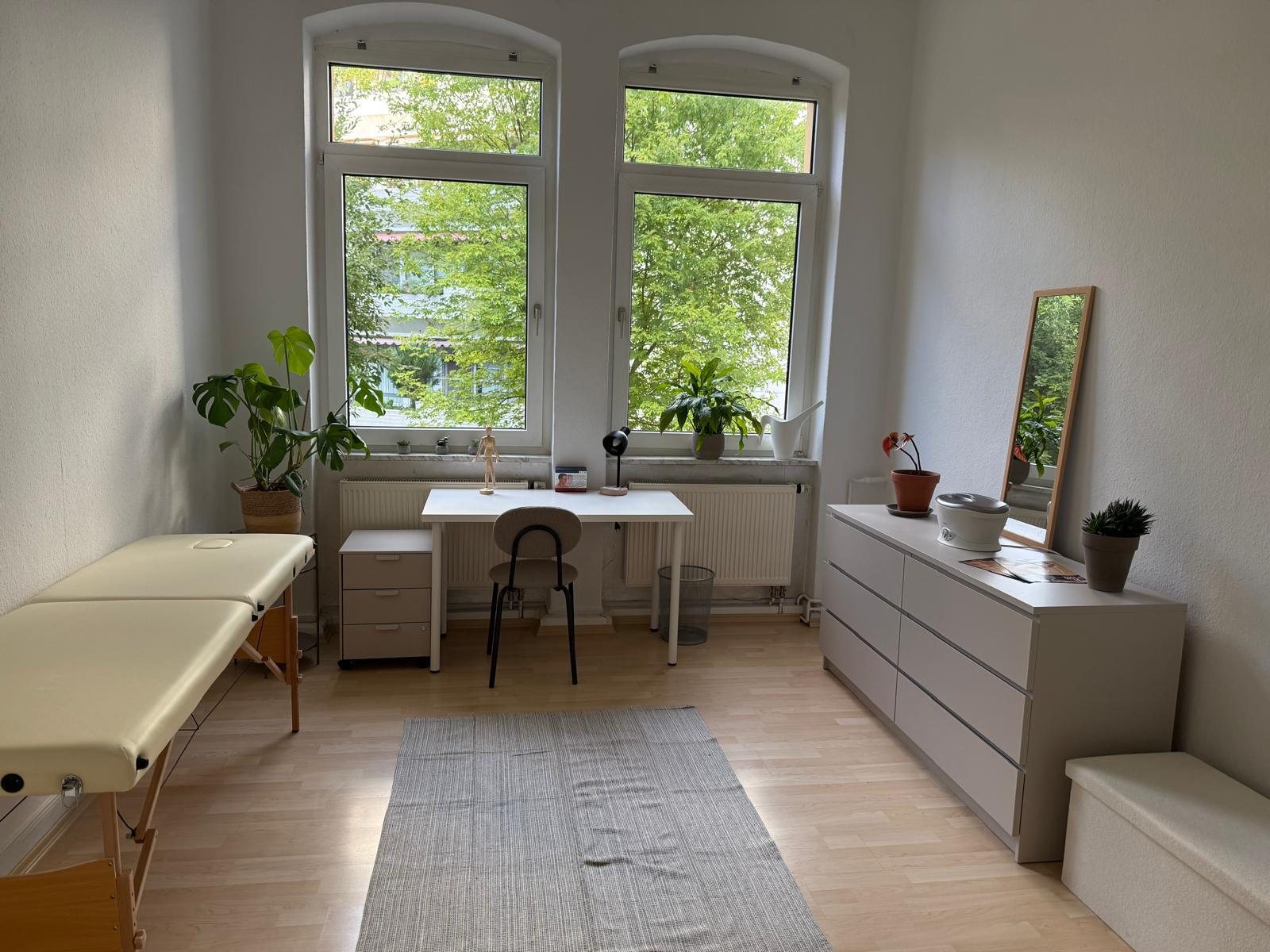 Behandlungsraum mit Liege und großen Fenstern